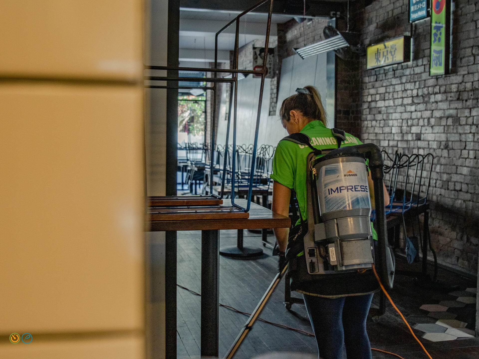 Pharo Cleaning staff vacuuming dining area floors before venue opening in a hospitality setting.