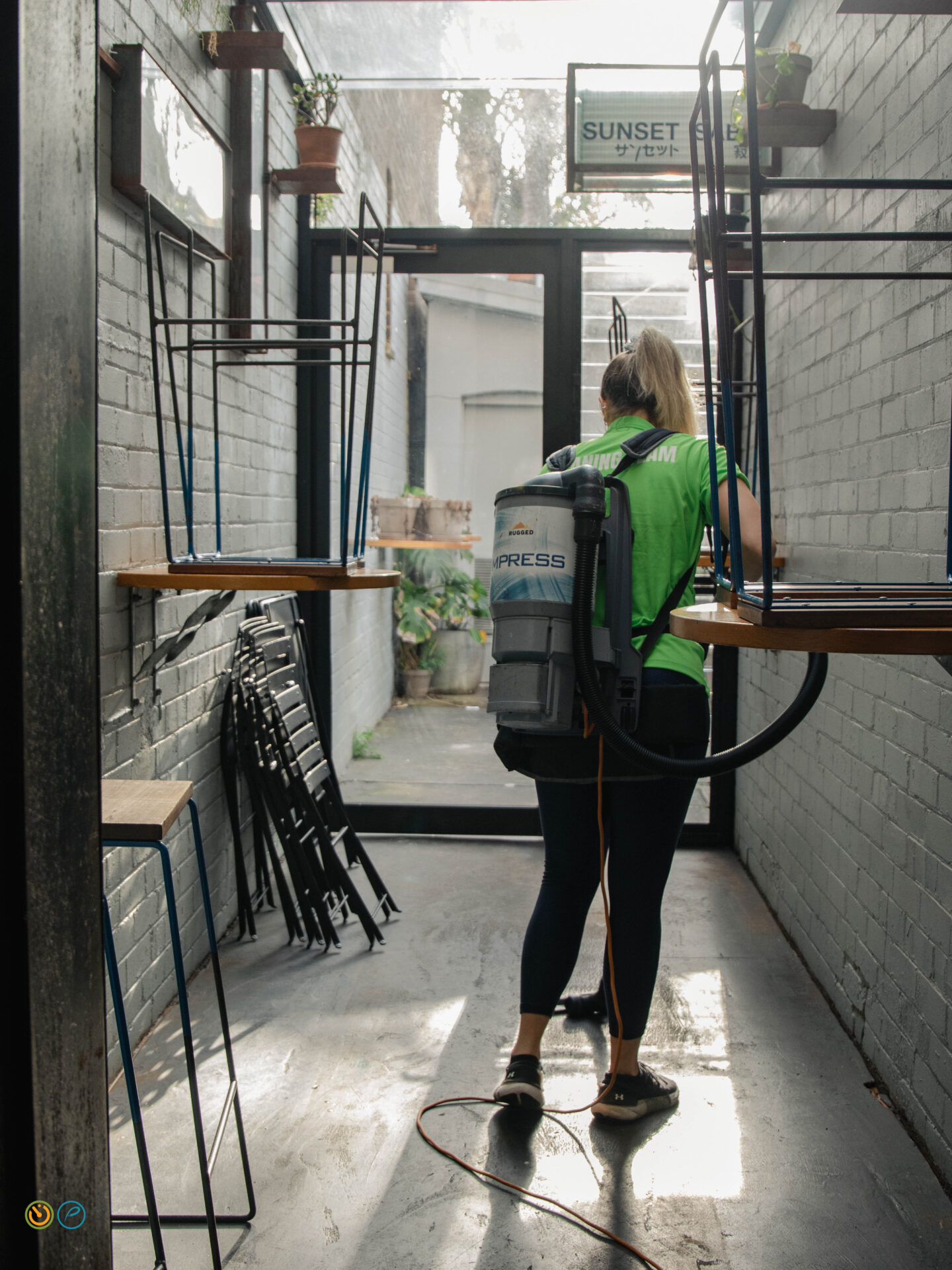 Hospitality cleaner vacuuming a restaurant floor after service as part of commercial cleaning.